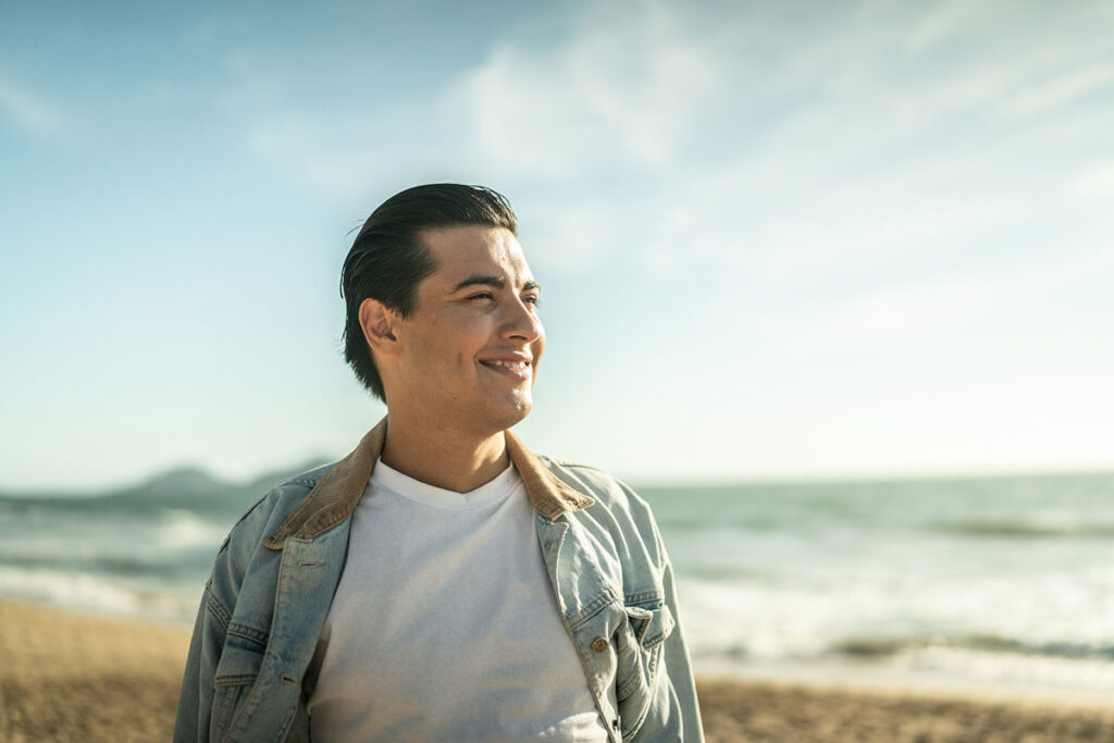 Young man looking away at the beach.