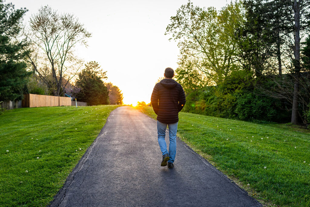 silhouette of man walking towards sunset